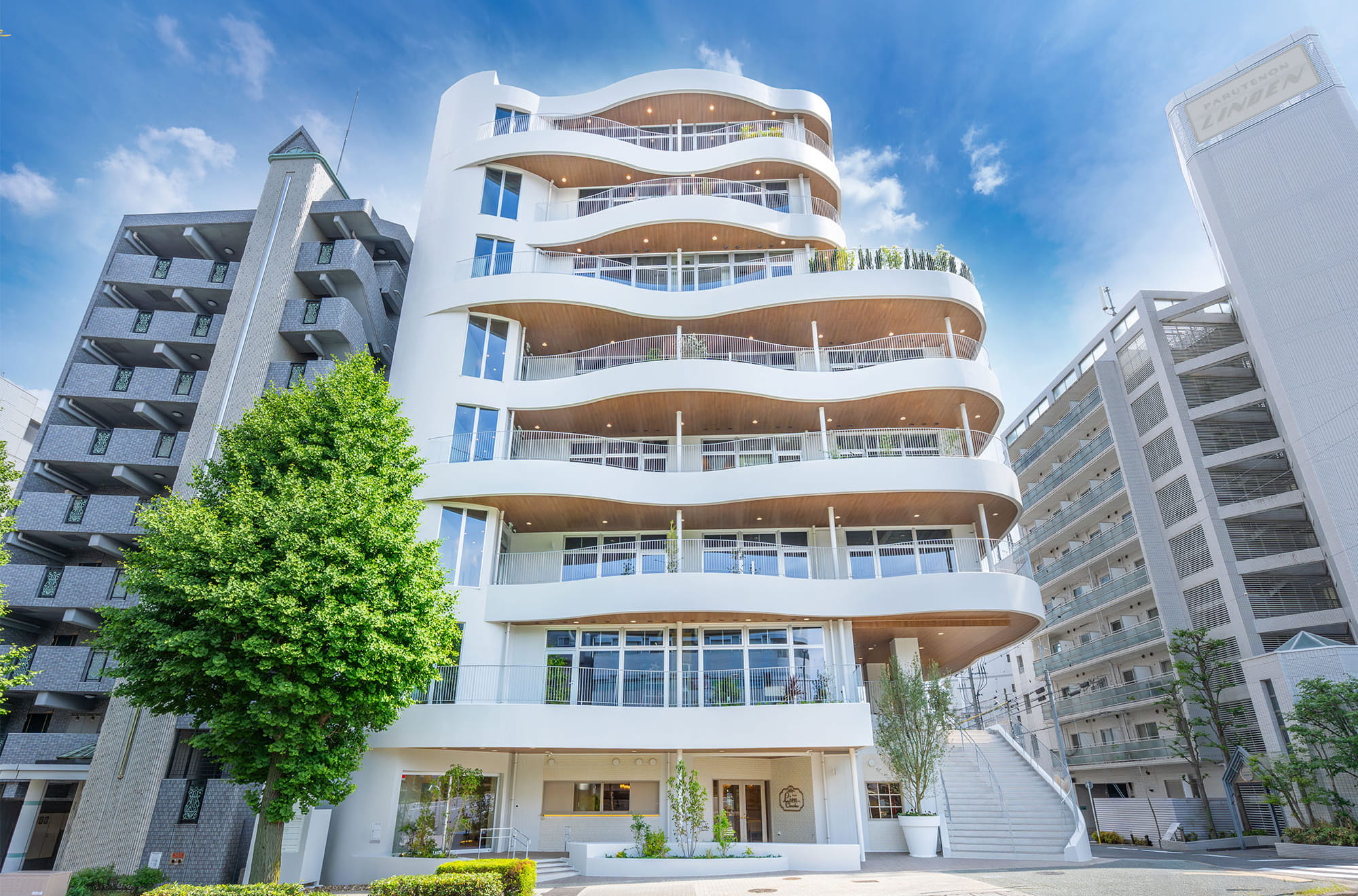 施工事例：曲線のバルコニーが重なる白い外観のマンション