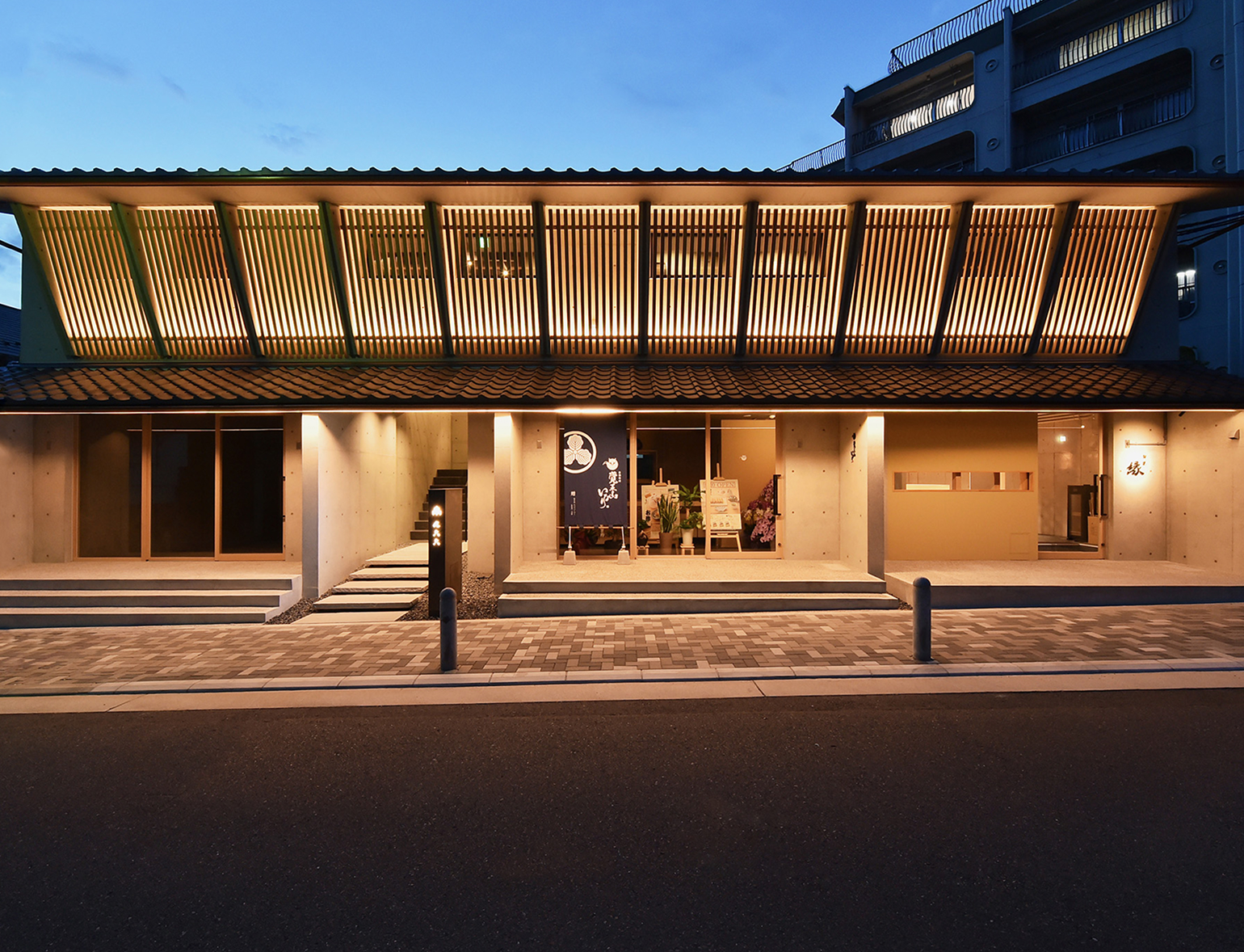 東海・ビルドグループの施工事例。木製ルーバーの大屋根が照らされた建物の夜景